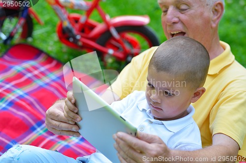 Image of grandfather and child in park using tablet