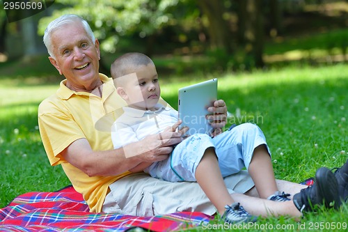 Image of grandfather and child in park using tablet