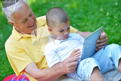 Image of grandfather and child in park using tablet