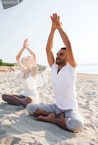 Image of smiling couple making yoga exercises outdoors