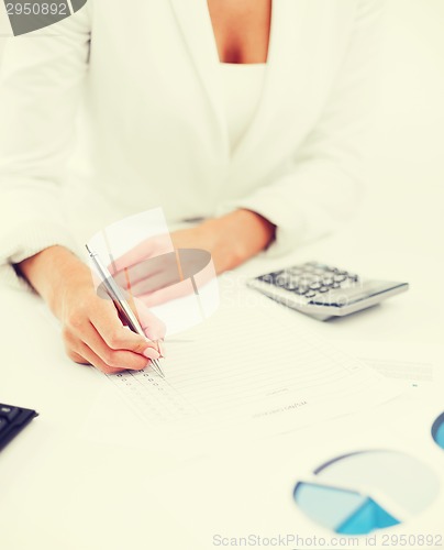 Image of businesswoman working with calculator in office