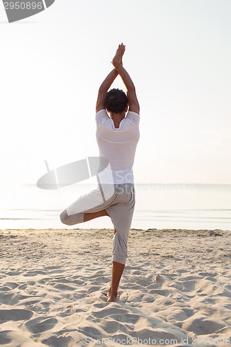 Image of man making yoga exercises outdoors from back