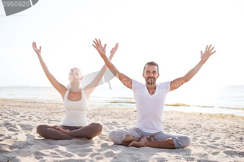 Image of smiling couple making yoga exercises outdoors