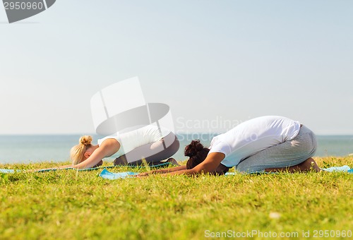 Image of couple making yoga exercises outdoors