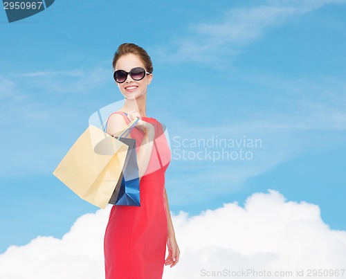 Image of smiling woman in red dress with shopping bags