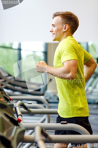 Image of smiling man exercising on treadmill in gym