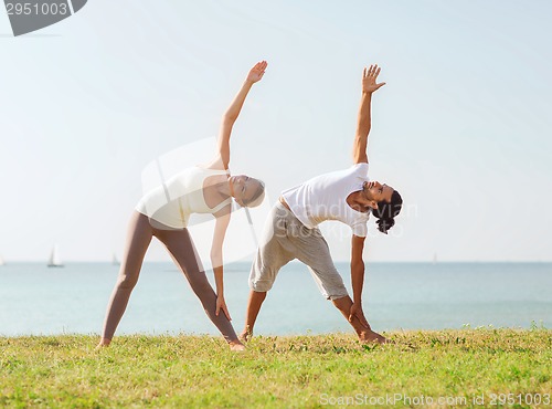 Image of couple making yoga exercises outdoors