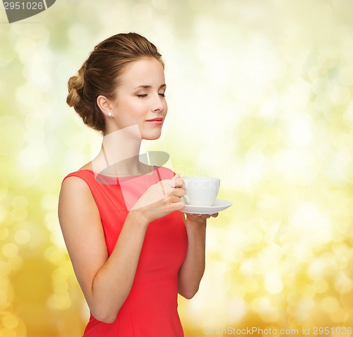 Image of smiling woman in red dress with cup of coffee