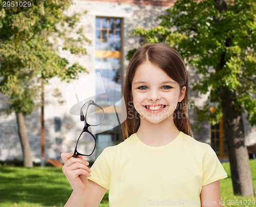 Image of smiling cute little girl holding black eyeglasses