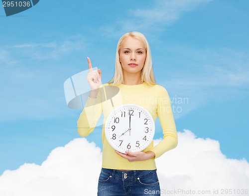 Image of student with wall clock and finger up