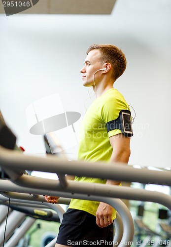 Image of man with smartphone exercising on treadmill in gym