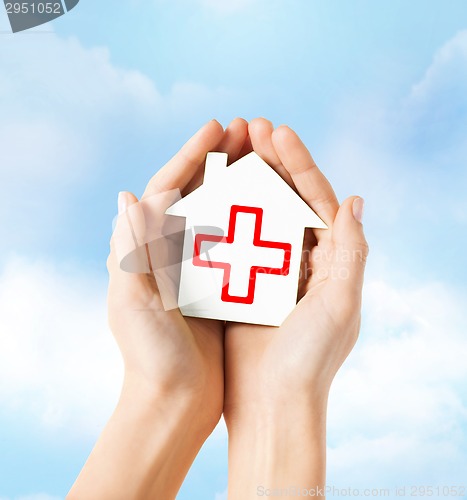 Image of hands holding paper house with red cross