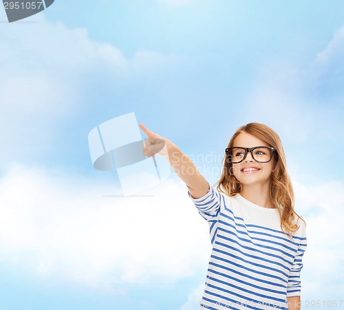 Image of cute little girl in eyeglasses pointing in the air