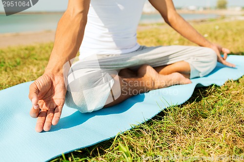 Image of close up of man making yoga exercises outdoors
