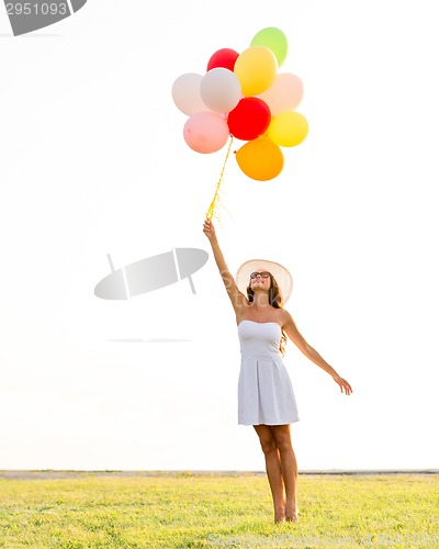 Image of smiling young woman in sunglasses with balloons