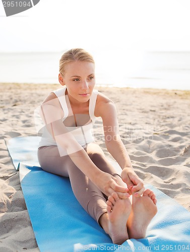 Image of young woman making yoga exercises outdoors