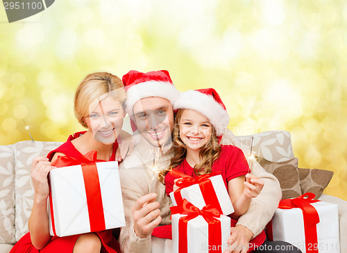 Image of smiling family holding gift boxes and sparkles