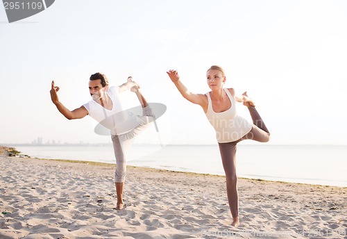 Image of couple making yoga exercises outdoors