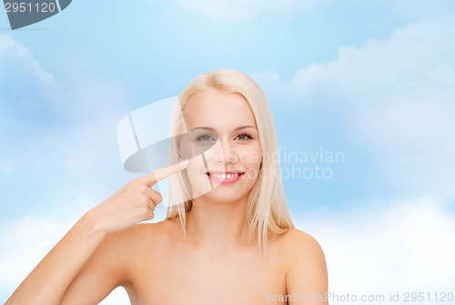 Image of smiling young woman pointing at her cheek