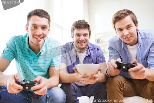 Image of smiling friends playing video games at home