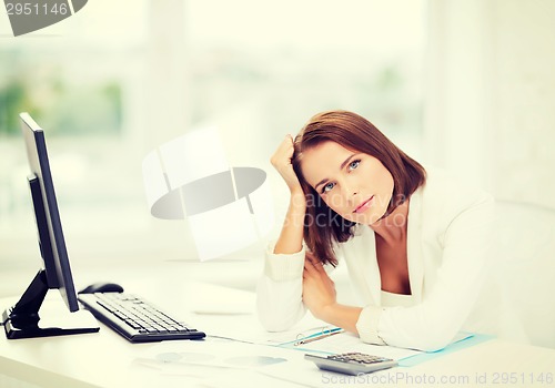 Image of woman with computer, papers and calculator