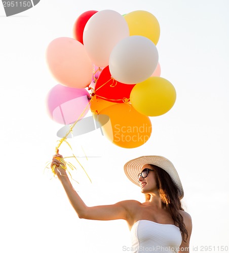 Image of smiling young woman in sunglasses with balloons