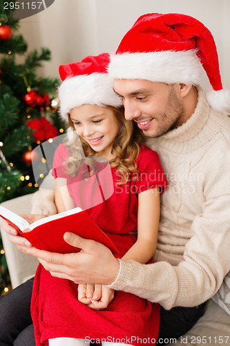 Image of smiling father and daughter reading book