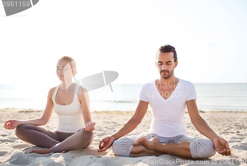 Image of smiling couple making yoga exercises outdoors