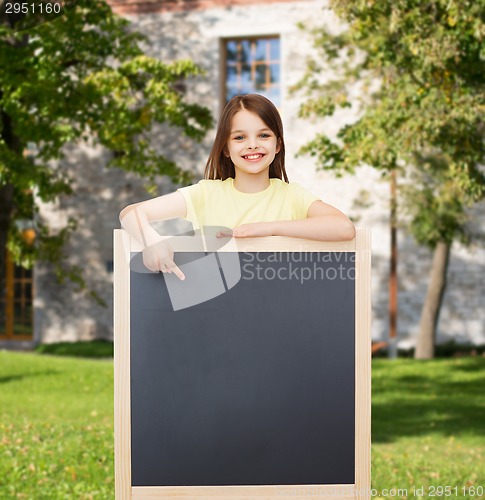 Image of happy little girl pointing finger to blackboard