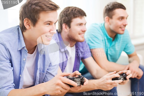 Image of smiling friends playing video games at home