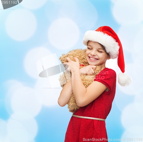 Image of smiling girl in santa helper hat with teddy bear