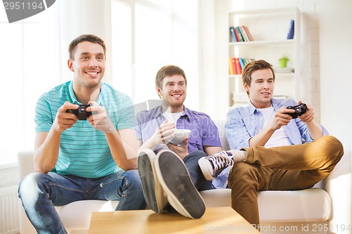 Image of smiling friends playing video games at home