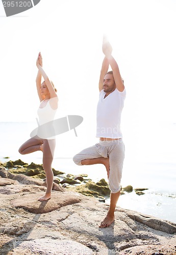 Image of couple making yoga exercises outdoors