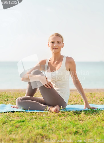 Image of young woman making yoga exercises outdoors