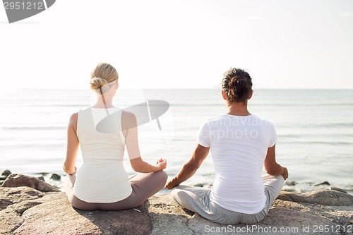 Image of couple making yoga exercises outdoors