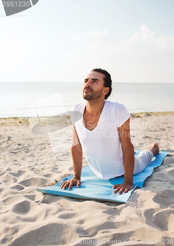 Image of man doing yoga exercises outdoors