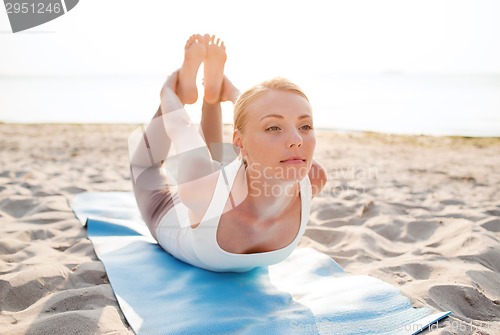 Image of young woman making yoga exercises outdoors