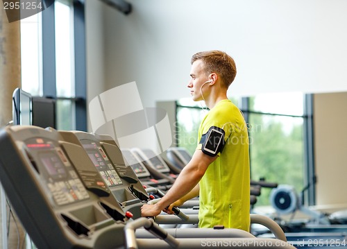 Image of man with smartphone exercising on treadmill in gym