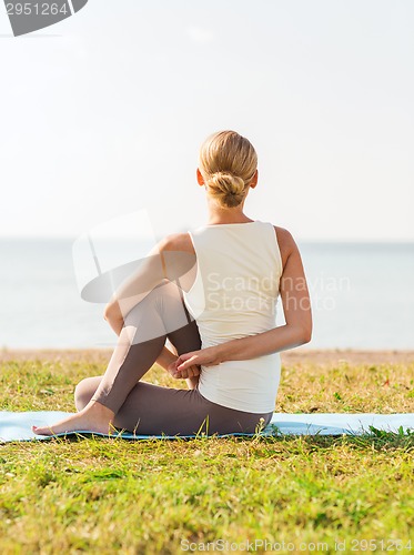 Image of woman making yoga exercises outdoors