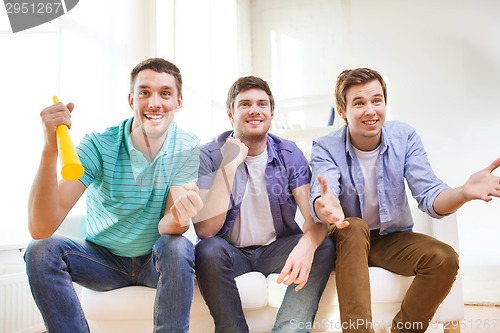 Image of happy male friends with vuvuzela