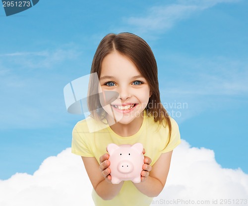 Image of beautiful little girl with piggy bank