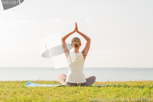 Image of woman making yoga exercises outdoors