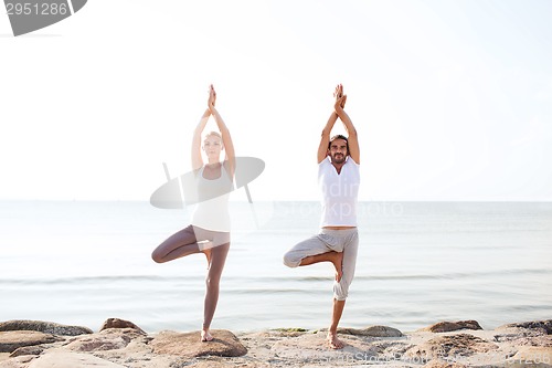 Image of couple making yoga exercises outdoors