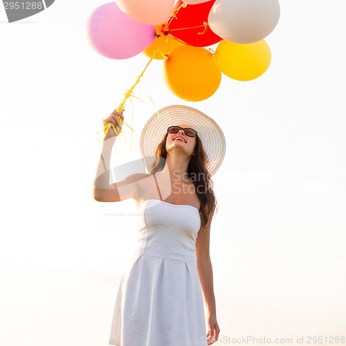 Image of smiling young woman in sunglasses with balloons