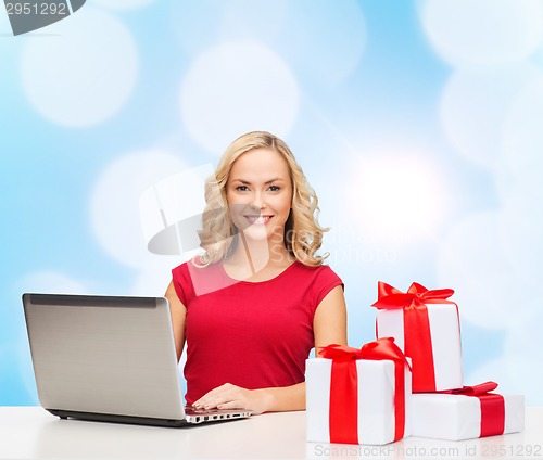 Image of smiling woman in red shirt with gifts and laptop