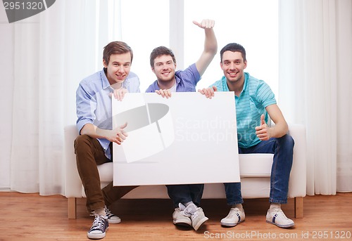 Image of happy male friends with blank white board at home