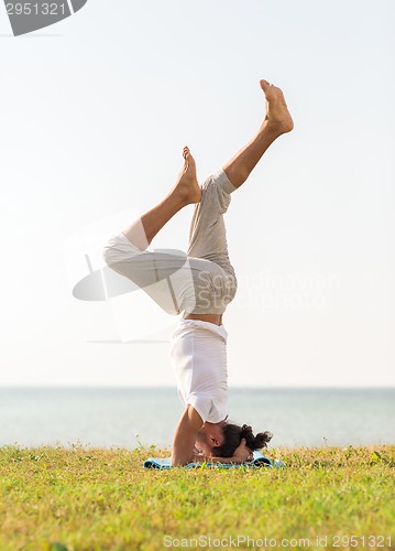 Image of man making yoga exercises outdoors