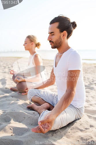 Image of smiling couple making yoga exercises outdoors