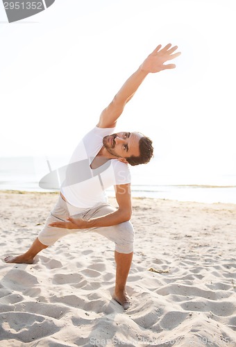 Image of smiling man making yoga exercises outdoors