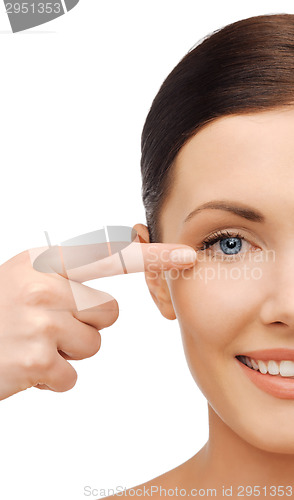 Image of young smiling woman pointing to her eye
